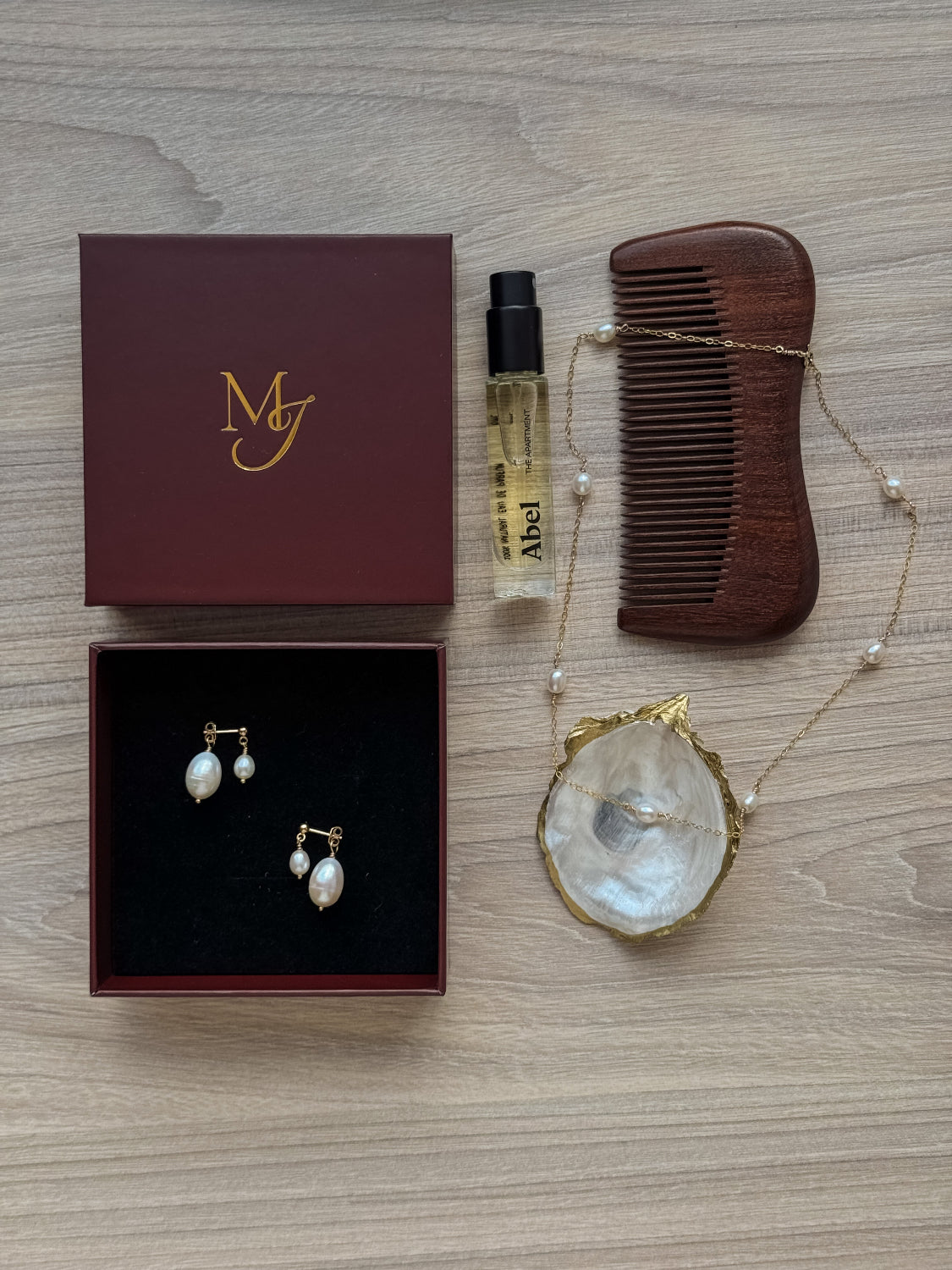 Collection of jewelry and beauty products including earrings, a comb, and a box on a wooden surface.