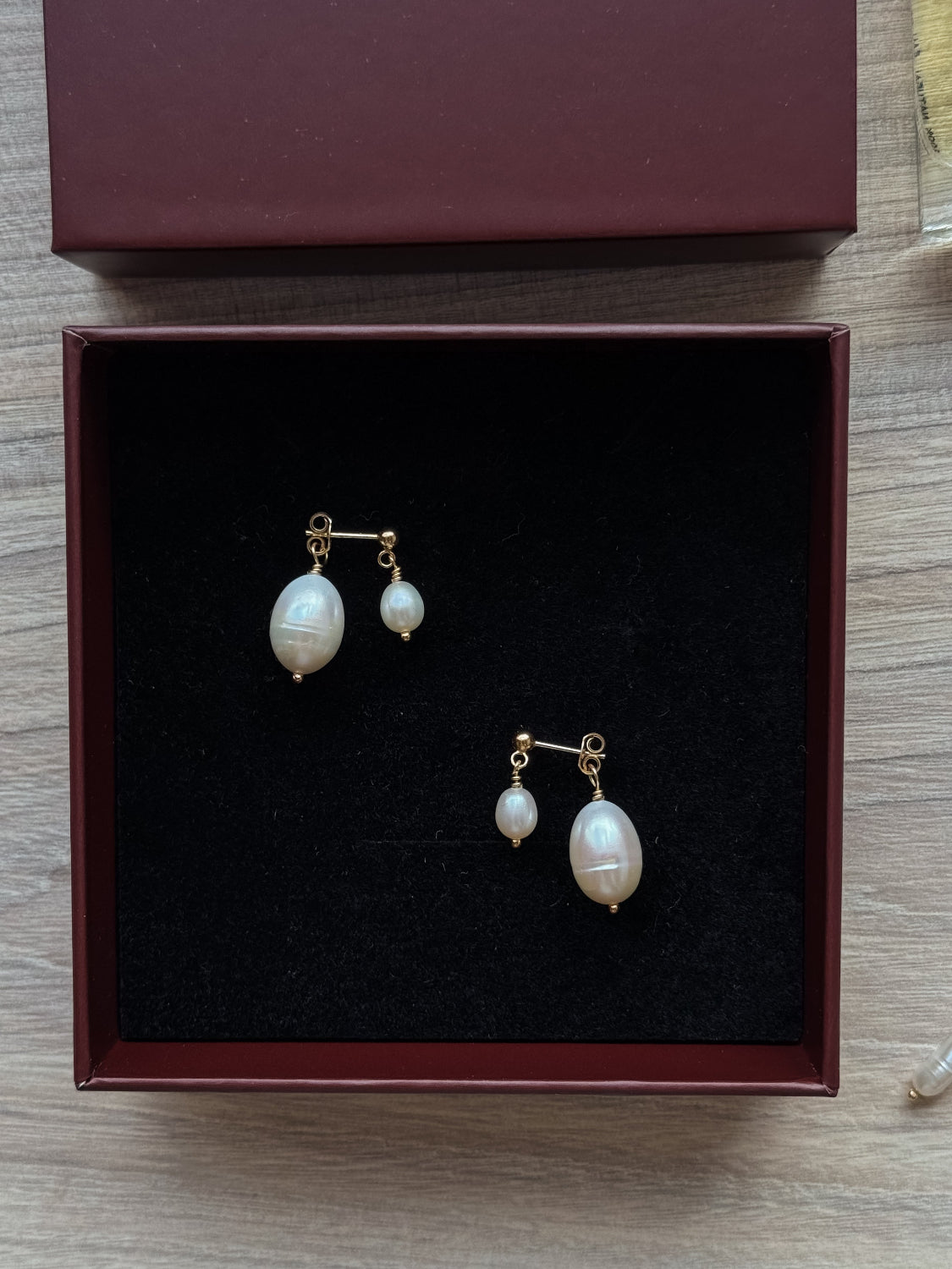 Pair of pearl earrings in a jewelry box on a wooden surface
