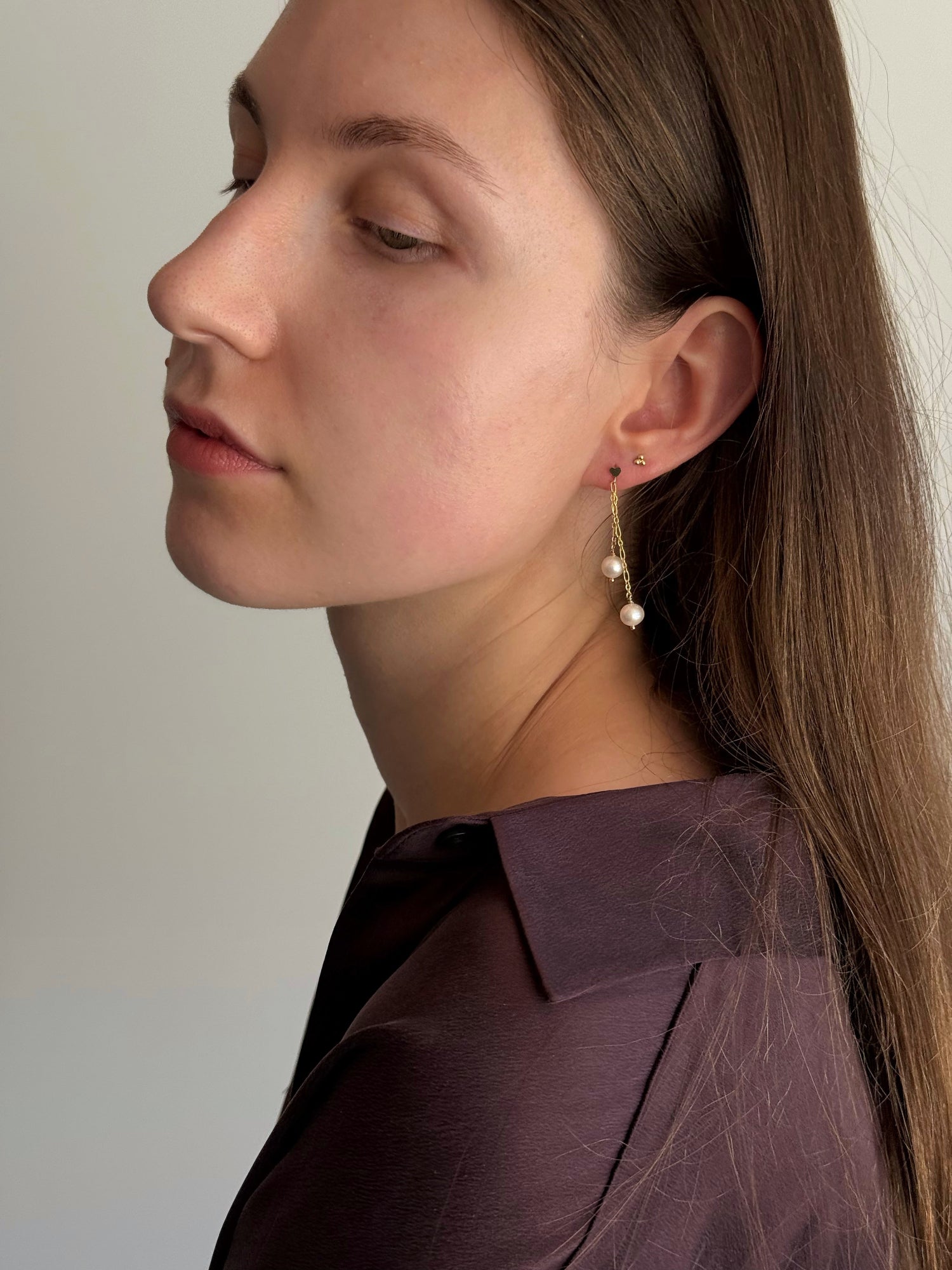 Close-up of a woman wearing pearl earrings with a neutral background