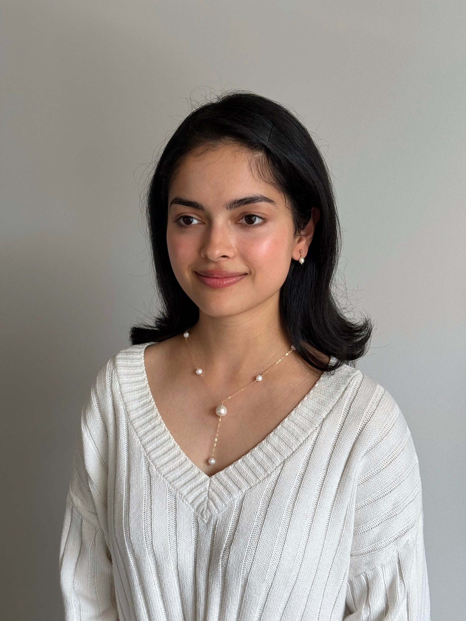 Model wearing minimalist pearl studs with hair tucked behind the ear