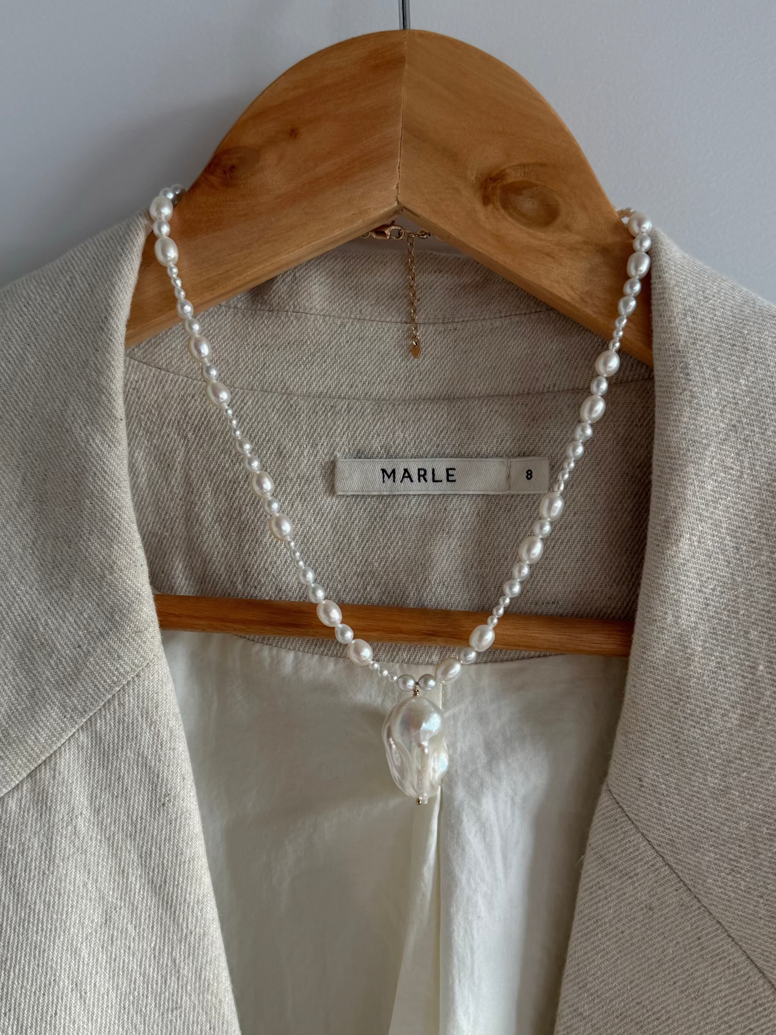 A graduated freshwater pearl necklace with a sculptural baroque pendant. 14k gold-filled findings, made to order in Wellington, New Zealand. styled with marle blazer