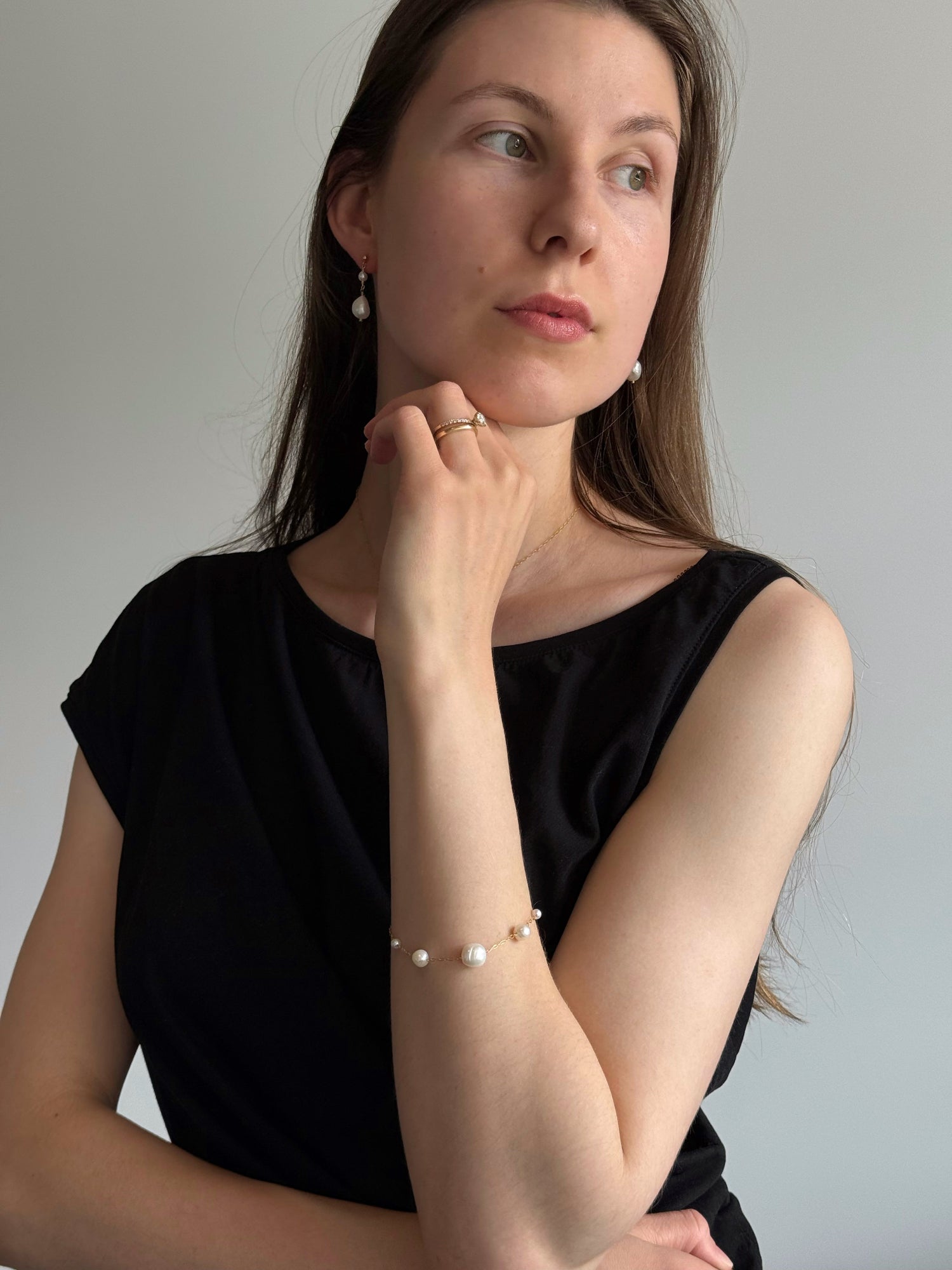 Woman wearing pearl jewelry against a plain background