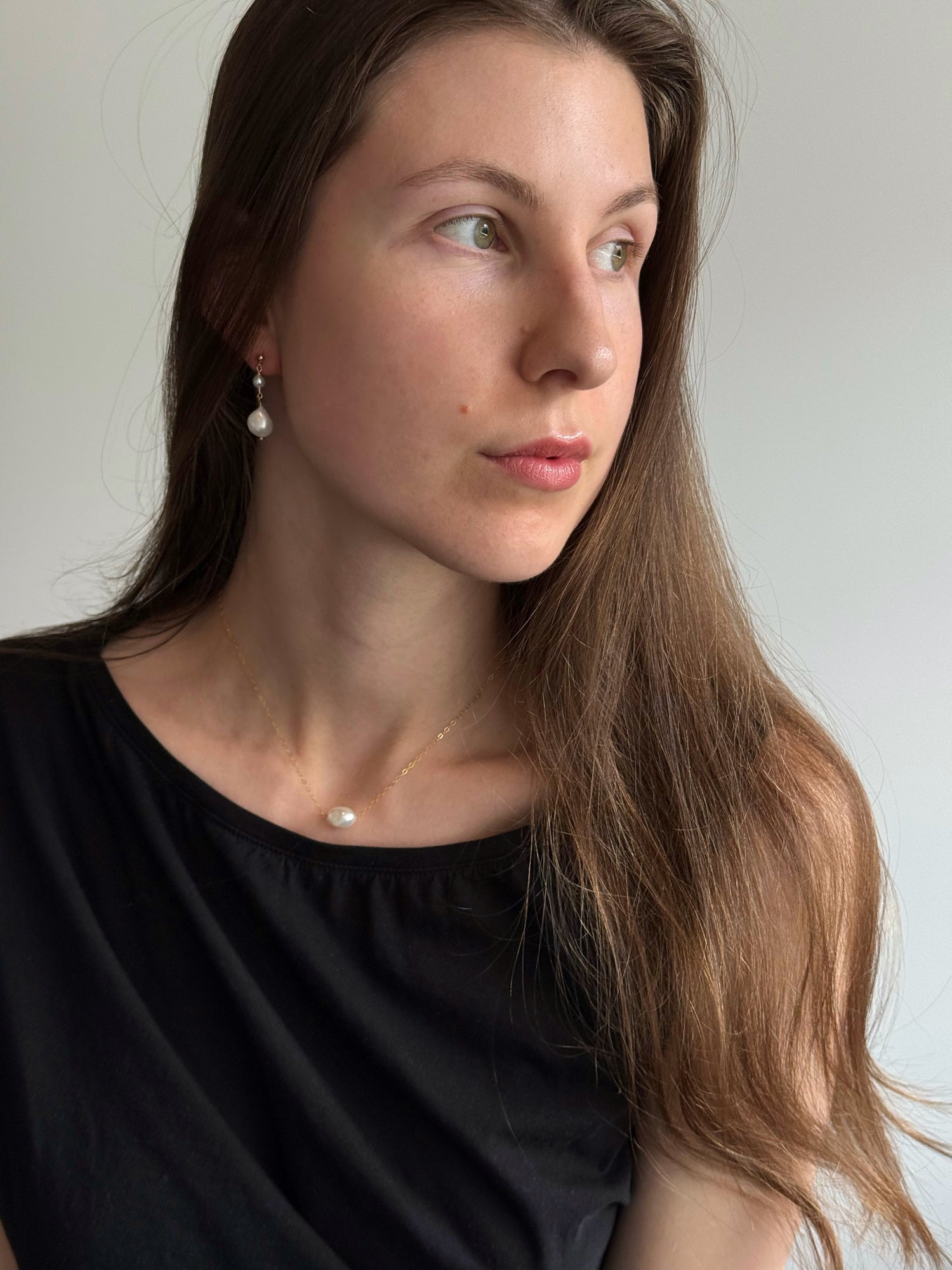 Model wearing pearl drop earrings with minimalist styling