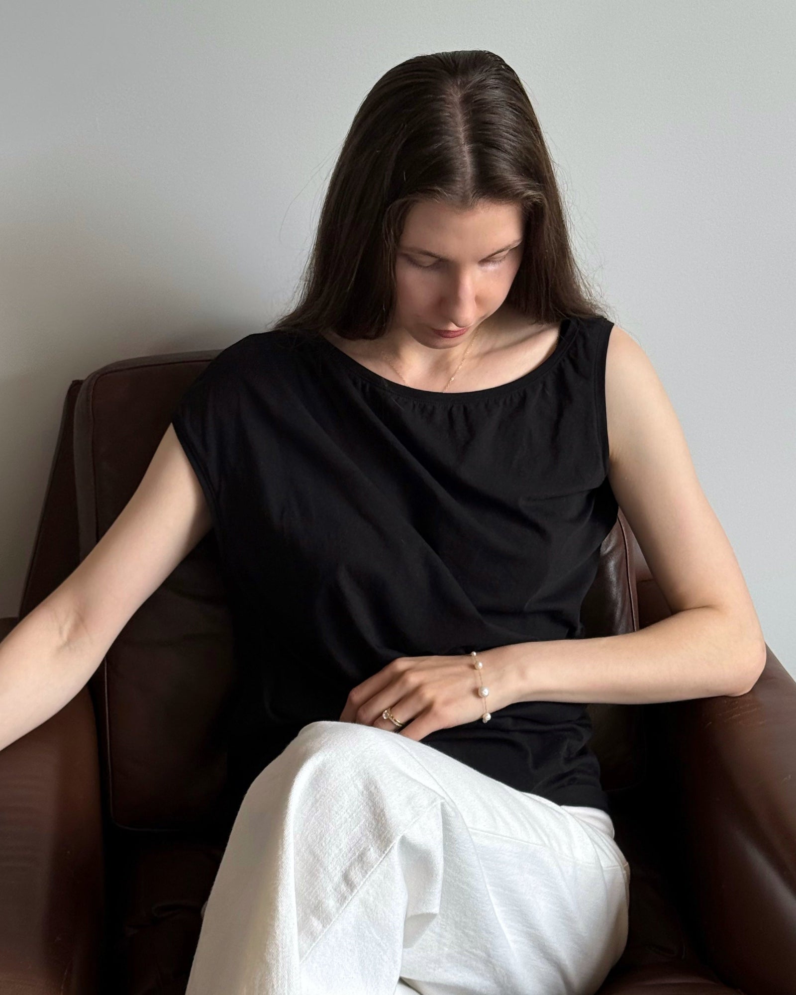 Woman sitting on a brown chair wearing a pearl statement bracelet
